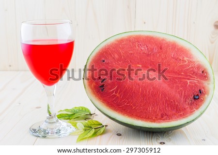 Watermelon juice in a wine glass with half water melon on wood floor background