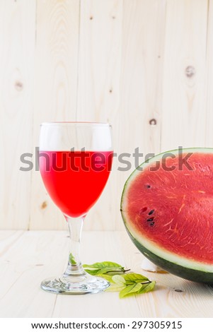 Watermelon juice in a wine glass with half water melon on wood floor background