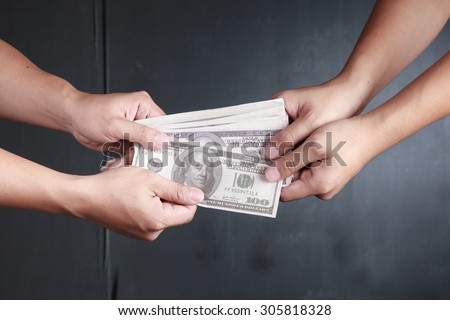 Two people passing a stack of one hundred dollar bills from hand to hand