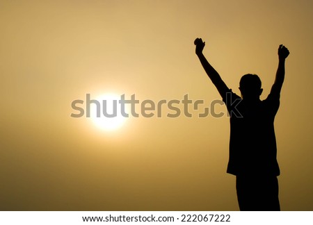 Man with his hands up watching the sun set