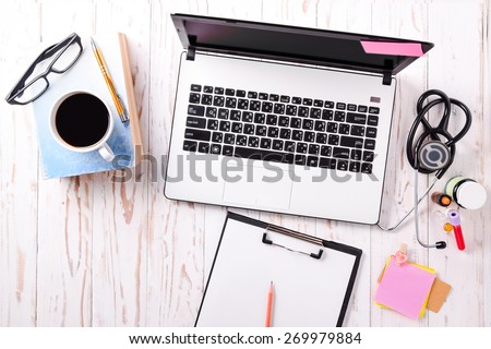 Doctor office,Top view ,Laptop (notebook) with cup of coffee and notepad,book with pen and  stethoscope with medicine on wood table.