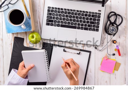 Doctor office,Top view ,Laptop (notebook) with cup of coffee and notepad,book with pen and  stethoscope with medicine on wood table.