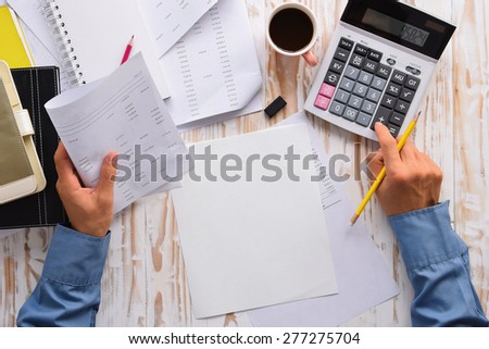 Top view businessmac use calculator and paper, cup of coffee, pencils and eraser on  white wooden table.Concept for Financial accounting