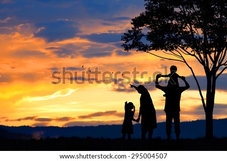 A silhouette of a happy family of five people, mother, father,girl,son and infant (women pregnancy) with tree on blurred sunset sky on mountain (copy space or text on left area)