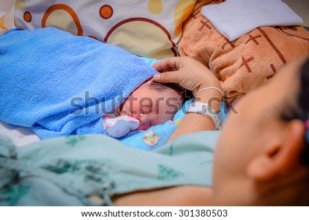 Newborn and Mother in hospital after giving birth (focused on newborn)