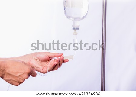Close up hand adjustment saline IV drip for patient in hospital with copy space