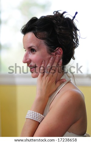 Dark-haired bride holds her hand to her face in surprise, showing her engagement ring.
