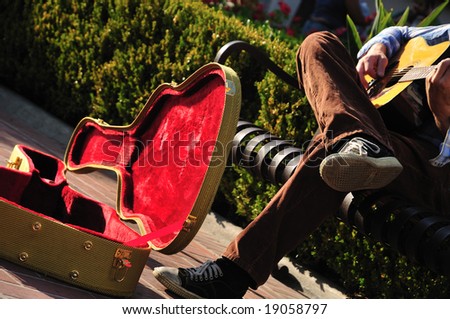 Red-lined guitar case of a street musician sitting on a bench