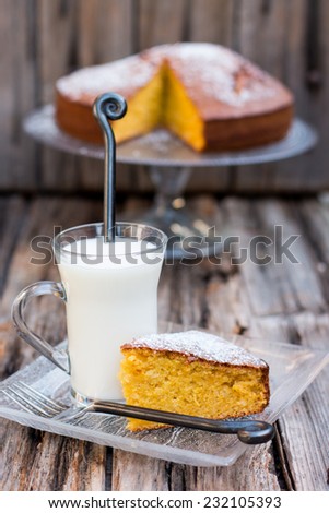 Pumpkin or carrot home-made cake with a cup of milk on a wooden table