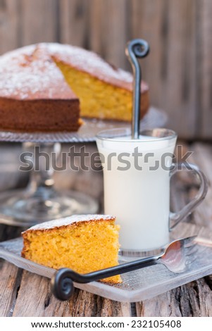 Pumpkin or carrot home-made cake with a cup of milk on a wooden table