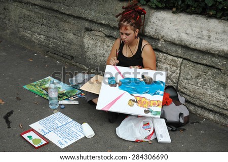 PARIS, FRANCE, AUGUST 17, 2006 - The young artist trying to make money for food for her daughter on street in Paris