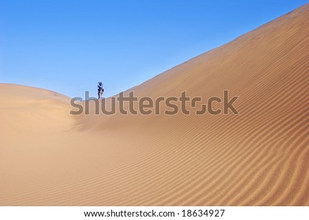 A surface of a sandy dune with hiking people