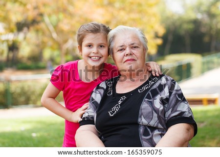 Portrait of a grandmother and granddaughter in the garden. Horizontal composition.