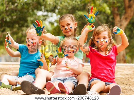 Five happy kids with hands covered in paint