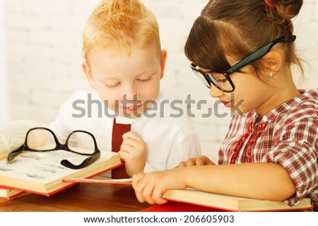 Two cute children nerds reading together.