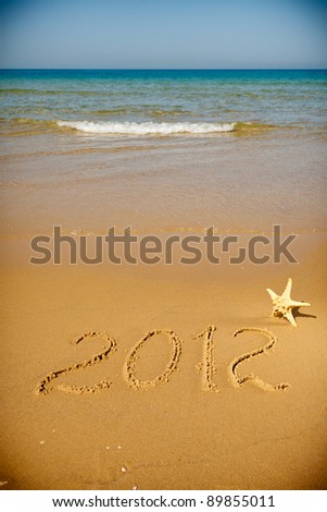 Handwritten message for year 2012 on deserted beach leaves room in clean sand