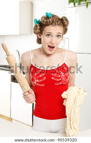 Cheerful housewife in the kitchen with the dough and rolling pin, at a loss