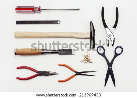 Overhead view of hand tools placed on white background. (hammer, chisel, pinchers, pincers and pliers and tweezers, scissors)