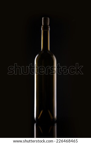 A yellow wine bottle with cork on the reflective bottom isolated black.