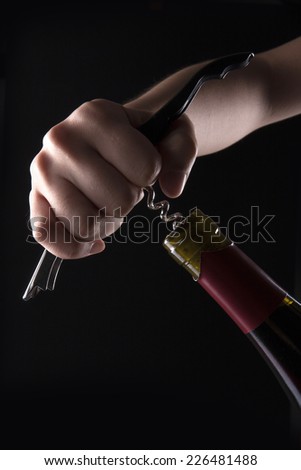 Two hands open the wine bottle with opener.