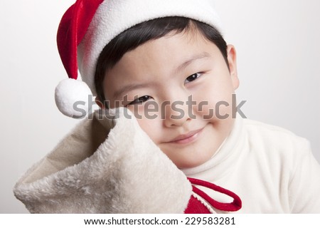 A asian(korea, japan, chinese, china) boy hold(hug) christmas socks for presents and wearing christmas hat with big smile isolated white at the studio.