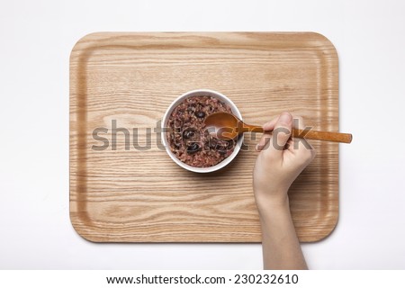 A female hand hold Multi-grain Rice with wood spoon on the wood tray isolated white, top view at the studio.