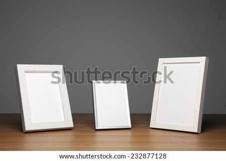 three empty(blank) wood photo frames(white) on the wood table(desk) at the studio.