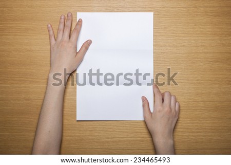 A female(woman) hands hold a empty(blank) white letter on the desk(table), top view at the studio.