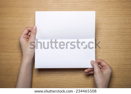 A female(woman) hands hold a empty(blank) white letter on the desk(table), top view at the studio.