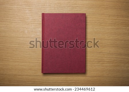 A blank(empty) red book(note, diary) cover on the wood desk(table), top view at the studio.