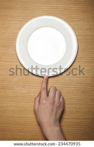 A female hands hold a empty(blank) white dish(plate) on the wood table(desk), top view at the studio.