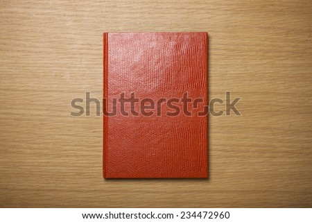 A blank(empty) red book(note, diary) cover on the wood desk(table), top view at the studio.