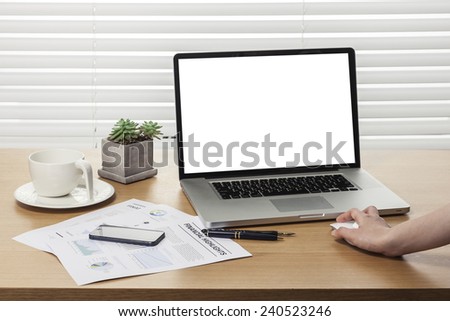 A working wooden desk(table) with notebook computer, tablet pc, mobile, hand phone, coffee cup, globe, pencil, behind white blind(roller blind) and hand.