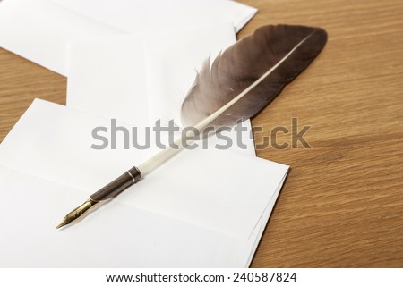 A feather quill pen, letter, envelope on the office desk(table) behind white blind.