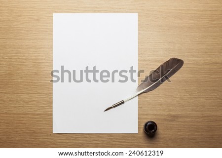A letter paper and feather quill pen, ink on the wood desk(table), top view at the studio.