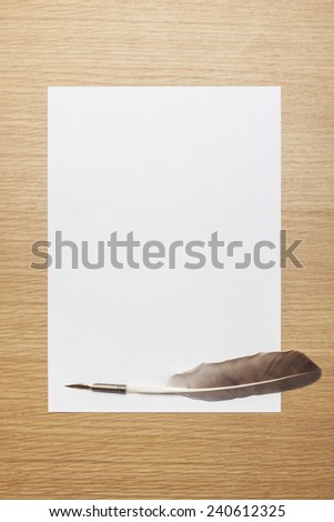 A letter paper and feather quill pen on the wood desk(table), top view at the studio.