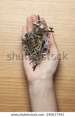 A female(woman) hand hold various vintage keys on the wood office desk(table) top view at the studio.