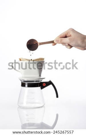 A female(woman) hold a brass coffee spoon and drop to the dropper and glass pot for hand- drip coffee isolated white at the studio.