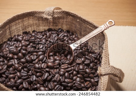 Coffee in the linen fabric bag with brass spoon on the table cloth, wood table(desk).