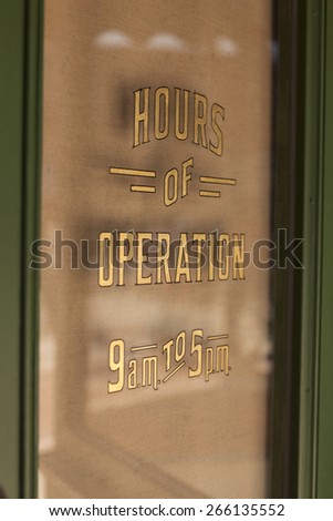 Open signage(hours of operation) printed in the vintage glass door.