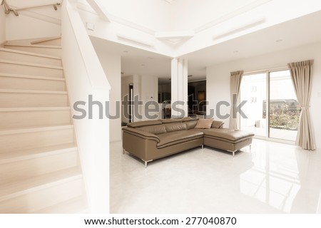 a brown leather sofa at the white living room on the marble bottom, double layered house with stair to second floor.