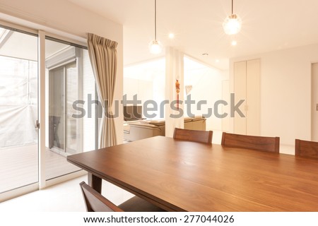A wood table and chairs at the kitchen and living room at the daylight.