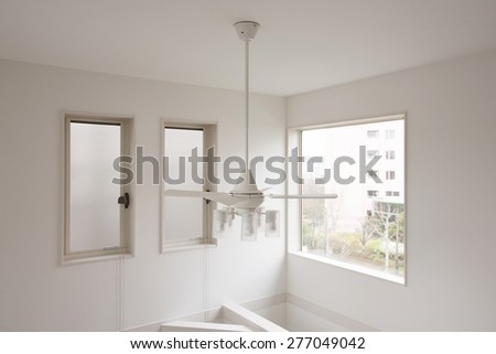 A white ceiling of double layered house with window and small light and fan.