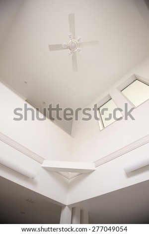 A white ceiling of double layered house with window and small light and fan.