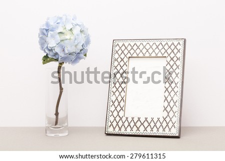 A light blue hydrangea(Hydrangea macrophylla for. otaksa) for wedding bouquet in the glass cup and photo frame on the paper table(desk) in the studio.