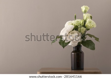 White and green roses for wedding bouquet in the flower vase on the wood table(desk) brown background in the studio.