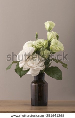 White and green roses for wedding bouquet in the flower vase on the wood table(desk) brown background in the studio.