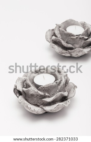 A white vintage(old) concrete candlestick with candle like flower(rose) isolated white background at studio.