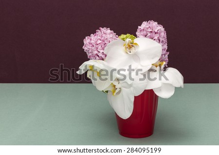 White Orchid flowers and pink Lavender flowers with red vase(cup) in the wine(chocolate) background on the emerald green bottom at the studio.