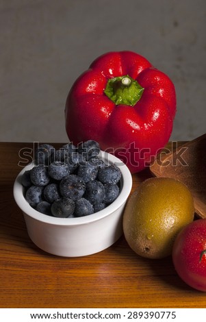 Many Variety fresh fruit(red sweet pepper, pimenta, bell pepper, pimento, blueberry, gold kiwi, red tomato) on the wood tray, table in the grey background at the studio.